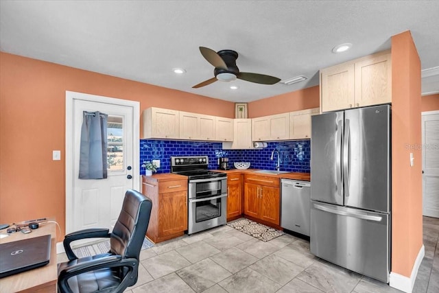 kitchen featuring appliances with stainless steel finishes, sink, backsplash, and ceiling fan