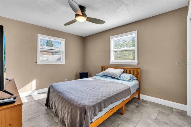 bedroom with ceiling fan, multiple windows, and a textured ceiling