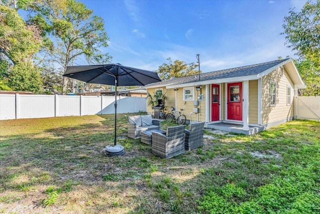 rear view of house with an outdoor hangout area, a yard, and an outbuilding