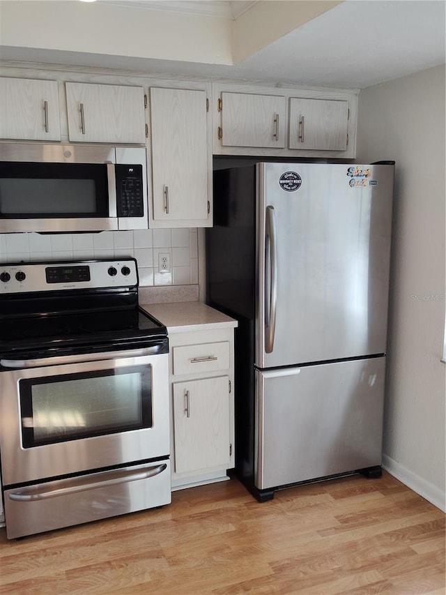 kitchen featuring tasteful backsplash, white cabinetry, appliances with stainless steel finishes, and light hardwood / wood-style flooring