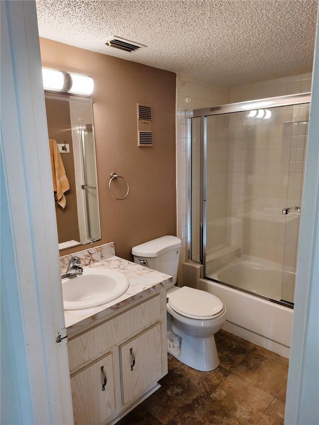 full bathroom featuring vanity, combined bath / shower with glass door, a textured ceiling, and toilet