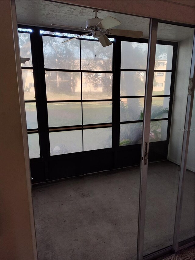 unfurnished sunroom with ceiling fan