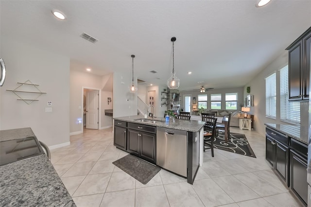 kitchen featuring sink, hanging light fixtures, a kitchen island with sink, stainless steel dishwasher, and light stone counters