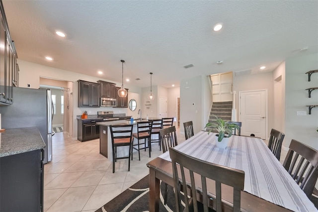 dining room featuring sink, a textured ceiling, and light tile patterned flooring