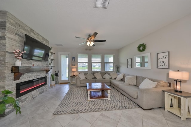 living room with light tile patterned flooring, a stone fireplace, and ceiling fan