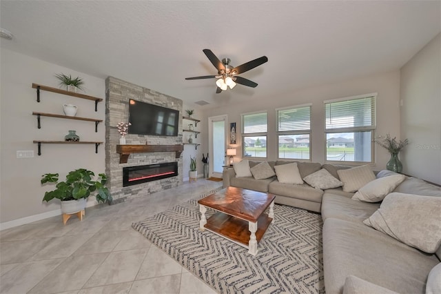 tiled living room featuring ceiling fan, a stone fireplace, and a textured ceiling