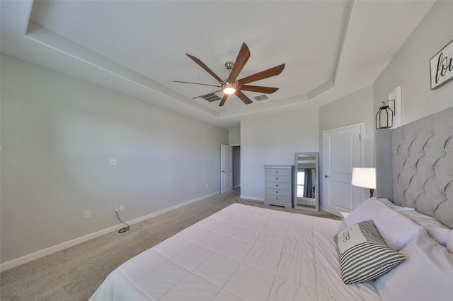 carpeted bedroom with a tray ceiling and ceiling fan