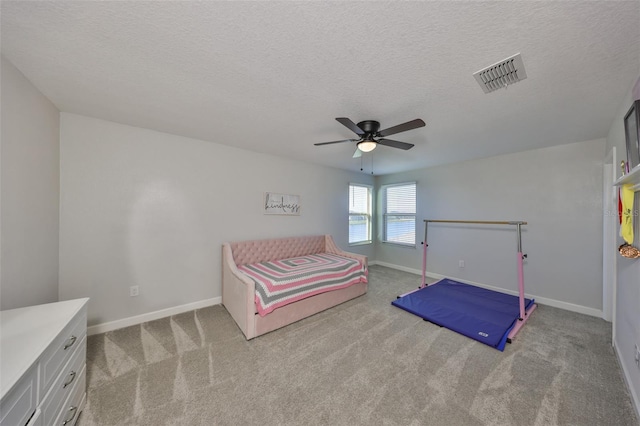 carpeted bedroom with ceiling fan and a textured ceiling