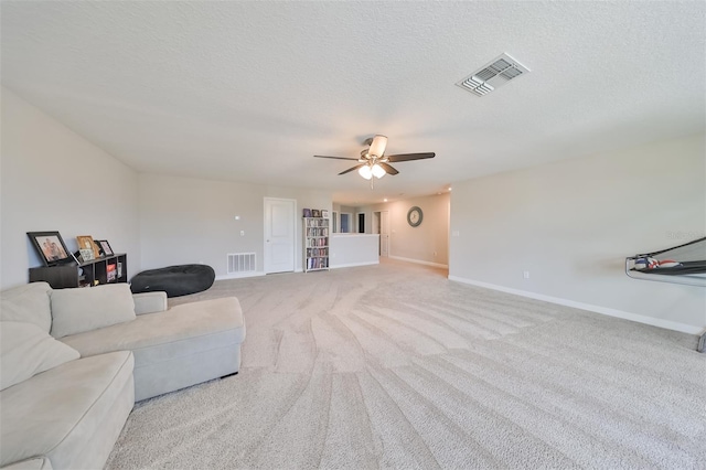 carpeted living room featuring ceiling fan and a textured ceiling