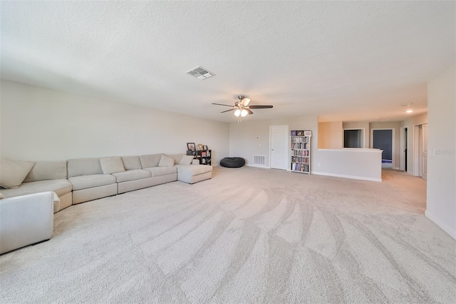 unfurnished living room with light carpet, ceiling fan, and a textured ceiling