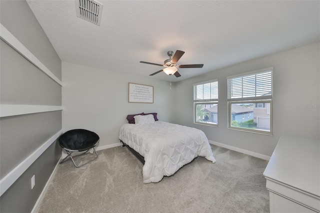 bedroom featuring ceiling fan, light colored carpet, and a textured ceiling