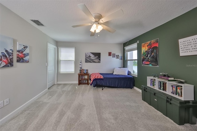 carpeted bedroom with multiple windows, ceiling fan, and a textured ceiling