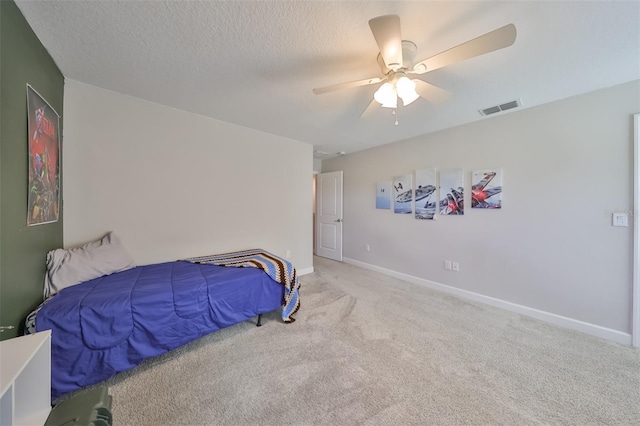 carpeted bedroom with ceiling fan and a textured ceiling