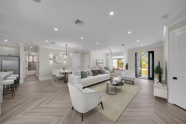 living room with an inviting chandelier, ornamental molding, and light parquet floors