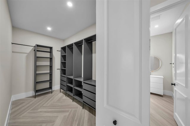 walk in closet with light parquet flooring