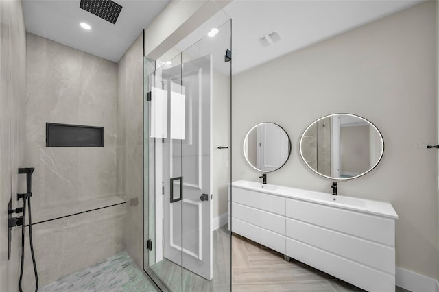 bathroom featuring parquet floors, tiled shower, and vanity