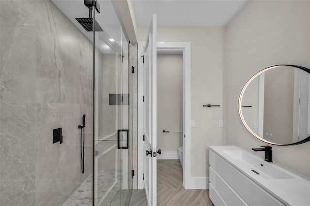 full bathroom with toilet, a stall shower, baseboards, and vanity