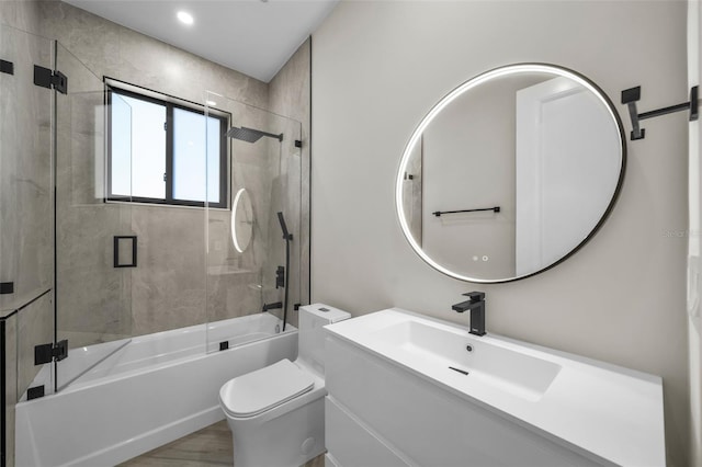 full bathroom with vanity, wood-type flooring, bath / shower combo with glass door, and toilet