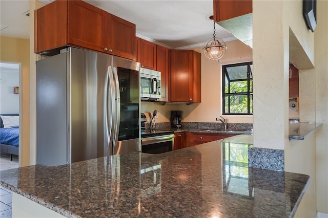 kitchen with sink, hanging light fixtures, dark stone countertops, appliances with stainless steel finishes, and kitchen peninsula