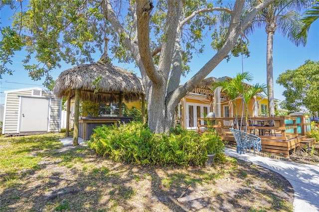 back of property with a storage unit, a deck, and a jacuzzi