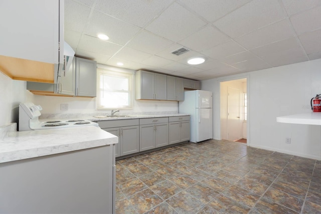 kitchen with gray cabinets, a paneled ceiling, sink, stove, and white fridge