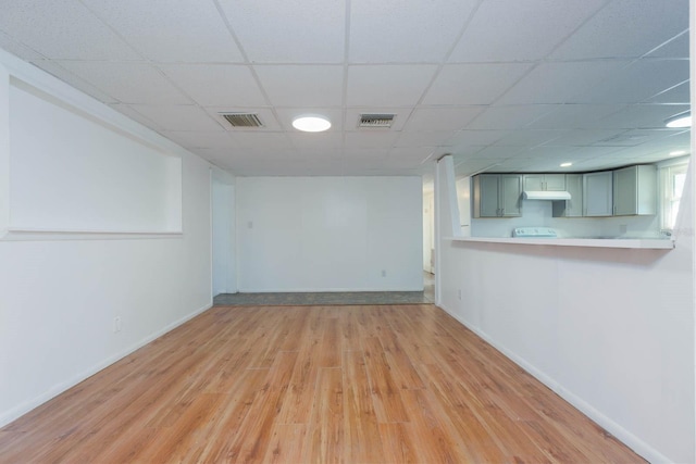 basement with a drop ceiling and light wood-type flooring