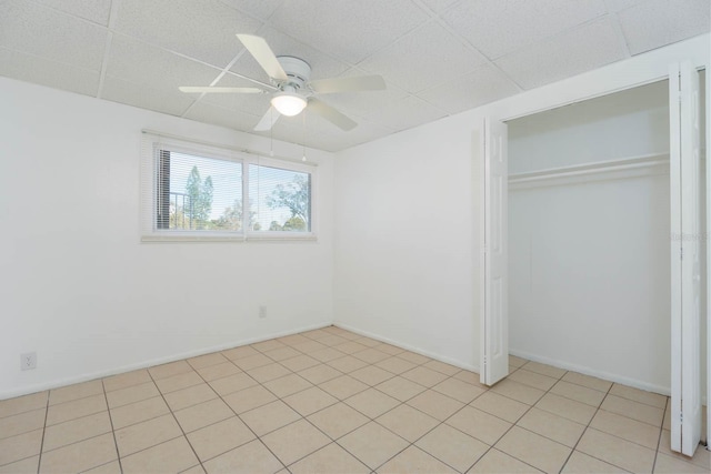 unfurnished bedroom with a paneled ceiling, ceiling fan, and a closet