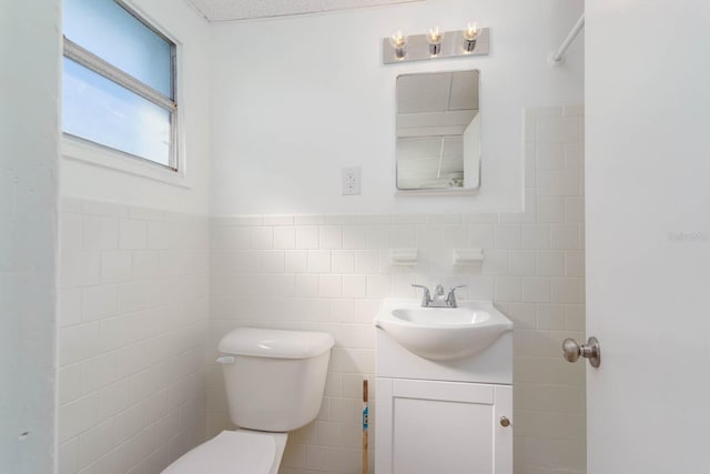 bathroom featuring vanity, tile walls, and toilet