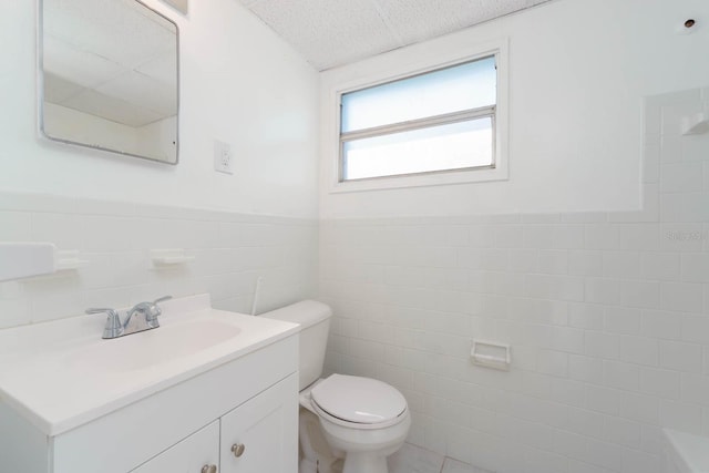 bathroom with vanity, a textured ceiling, tile walls, and toilet