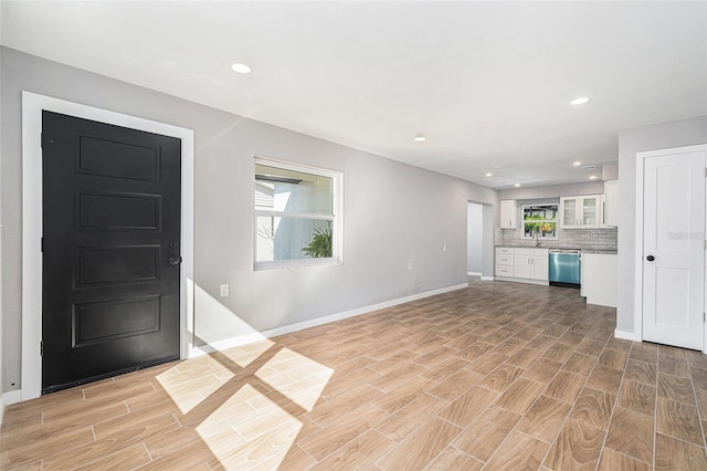 unfurnished living room with sink, plenty of natural light, and light wood-type flooring