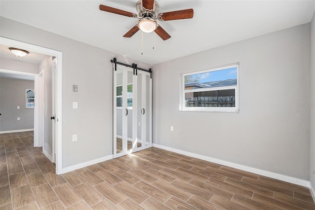 empty room featuring a barn door and ceiling fan