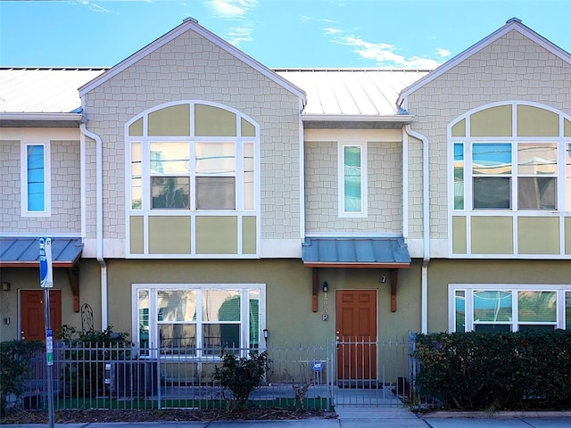 townhome / multi-family property featuring a standing seam roof, metal roof, and fence