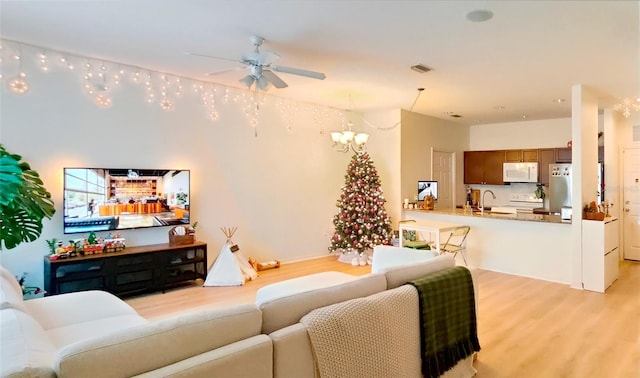 living room with sink, ceiling fan with notable chandelier, and light hardwood / wood-style floors