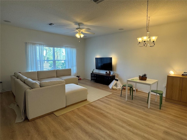 living room with light wood-style floors, visible vents, a textured ceiling, and ceiling fan with notable chandelier