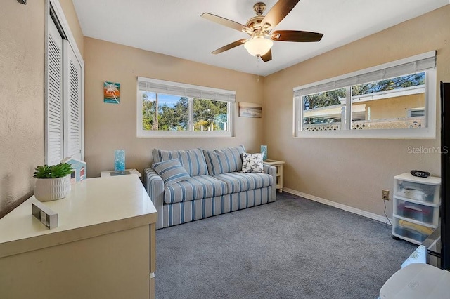 carpeted living area with ceiling fan, baseboards, and a healthy amount of sunlight