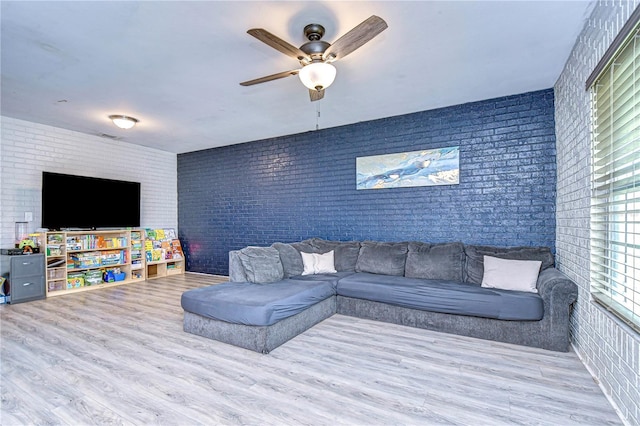 living room featuring ceiling fan, brick wall, and light hardwood / wood-style flooring