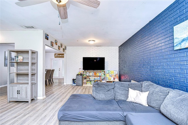 living room featuring ceiling fan, brick wall, and light wood-type flooring