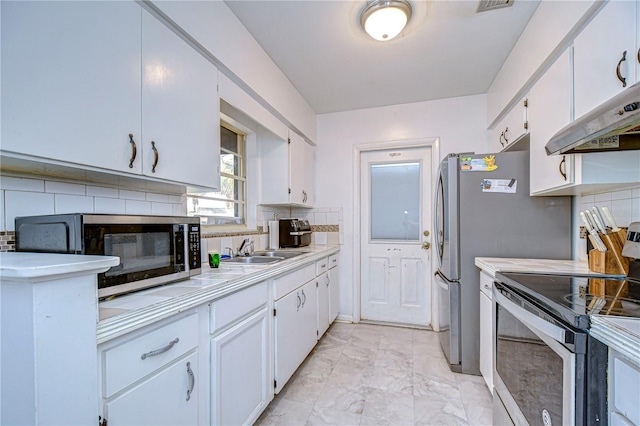 kitchen with stainless steel appliances, tasteful backsplash, sink, and white cabinets