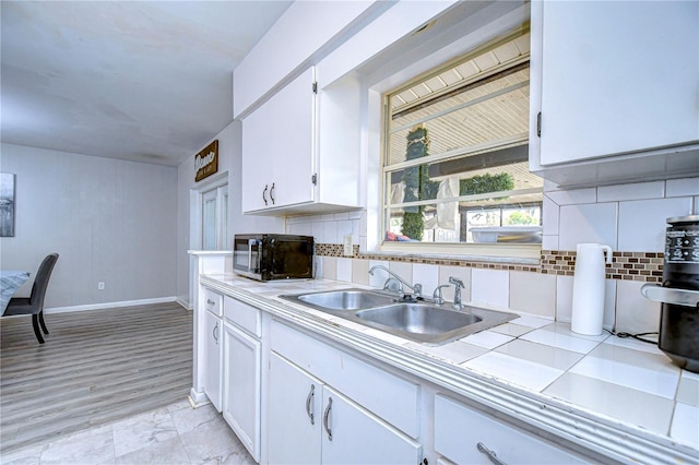 kitchen featuring sink, tile countertops, white cabinets, and decorative backsplash