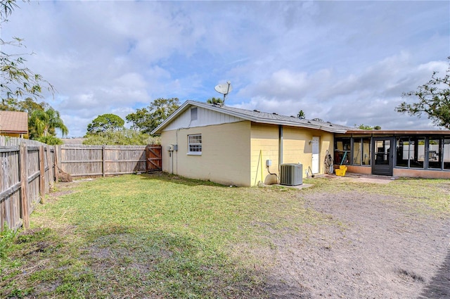 rear view of house with a sunroom, a yard, and central air condition unit