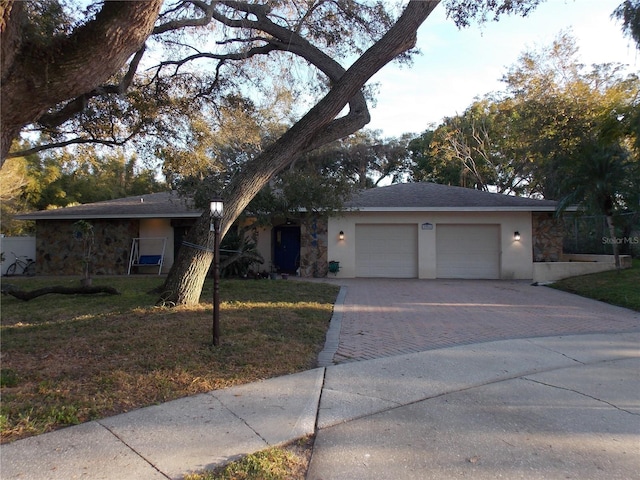 single story home with stone siding, decorative driveway, and stucco siding