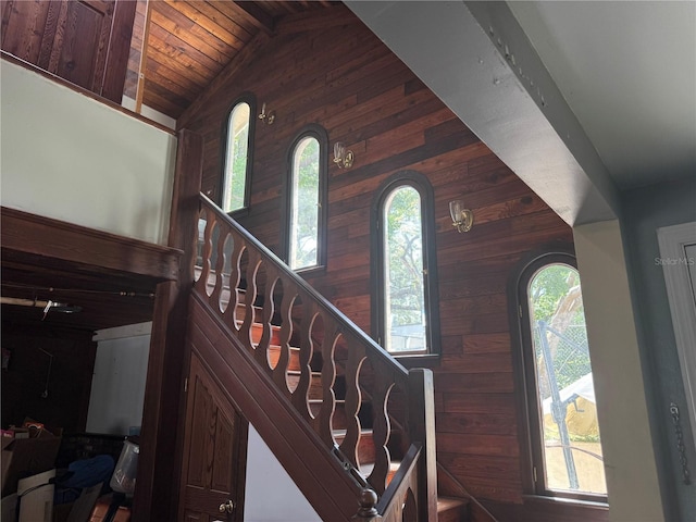 foyer featuring wood ceiling, vaulted ceiling, wood walls, and stairs