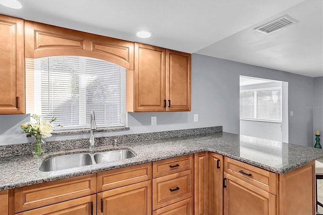 kitchen featuring sink, plenty of natural light, kitchen peninsula, and stone countertops