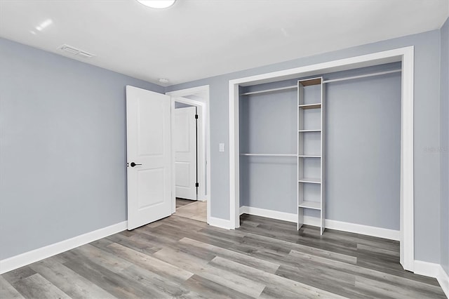 unfurnished bedroom with wood-type flooring and a closet