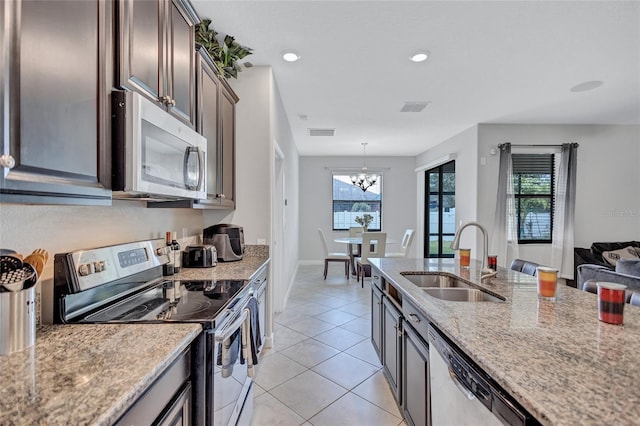 kitchen with sink, appliances with stainless steel finishes, a wealth of natural light, light tile patterned flooring, and decorative light fixtures