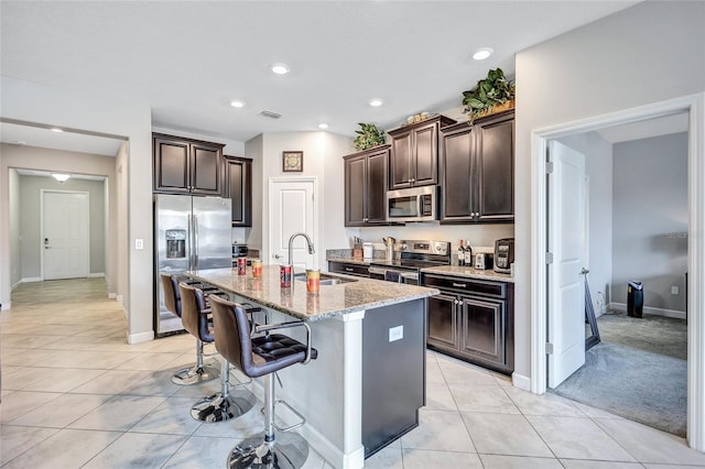 kitchen featuring light tile patterned flooring, sink, a breakfast bar area, a kitchen island with sink, and stainless steel appliances