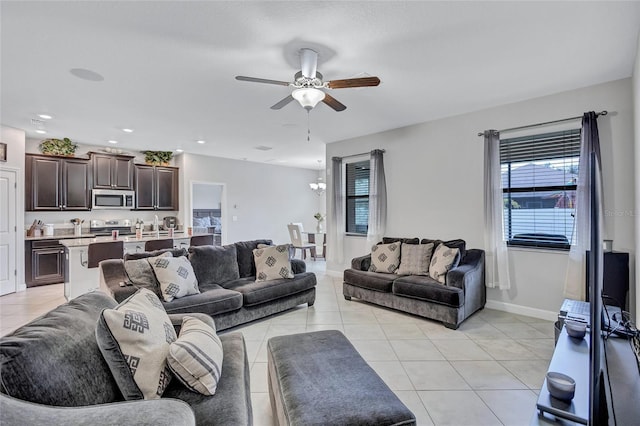 tiled living room with ceiling fan with notable chandelier