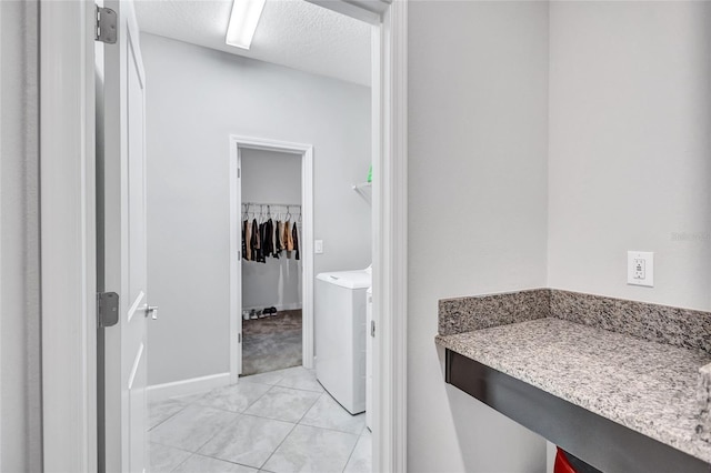 bathroom featuring washer / clothes dryer, tile patterned flooring, and a textured ceiling