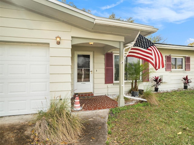 property entrance featuring a garage and a lawn