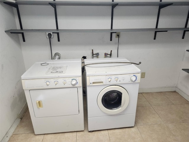 washroom with washer and dryer, light tile patterned flooring, and laundry area